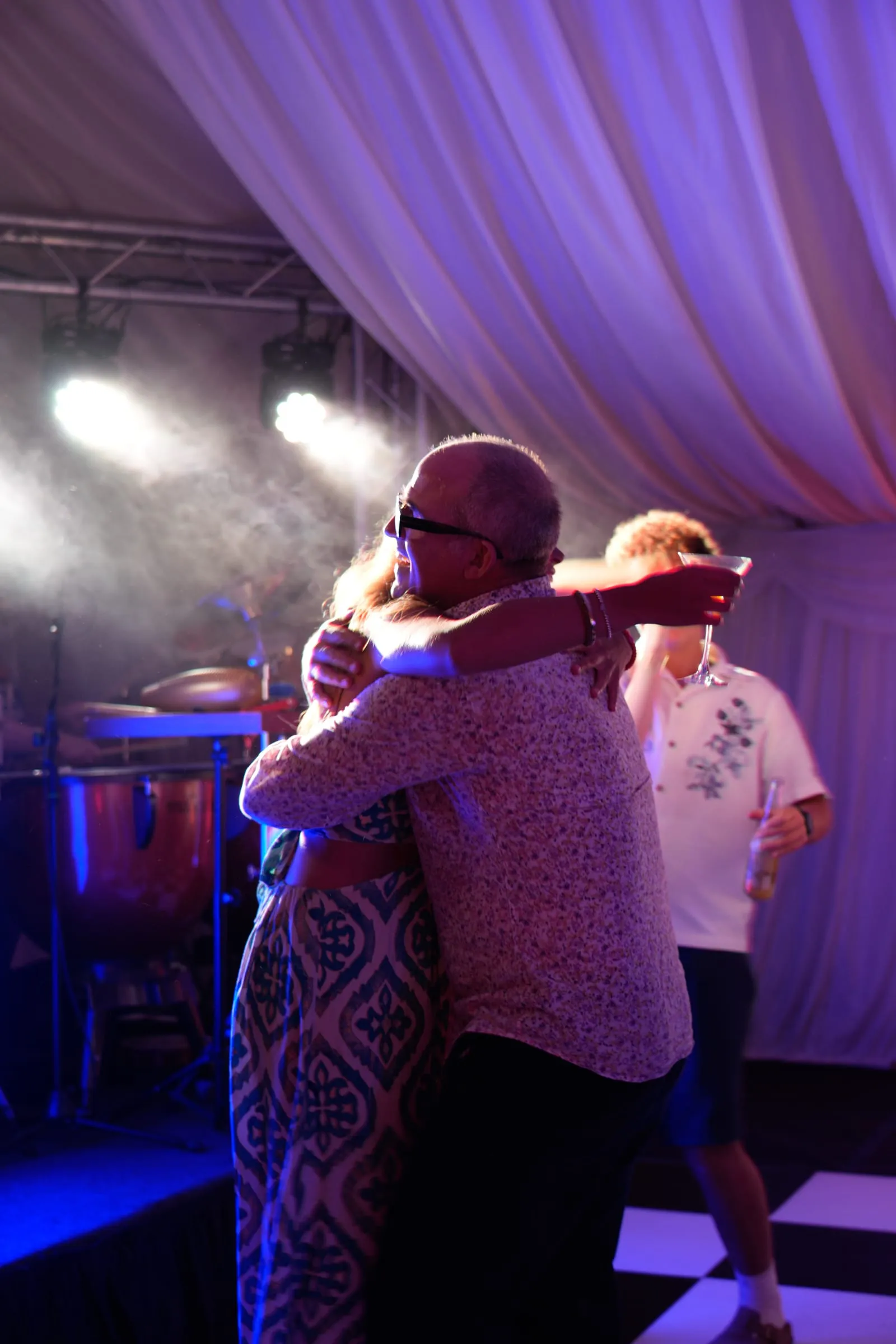 Two guests embrace on the dance floor under spotlights.
