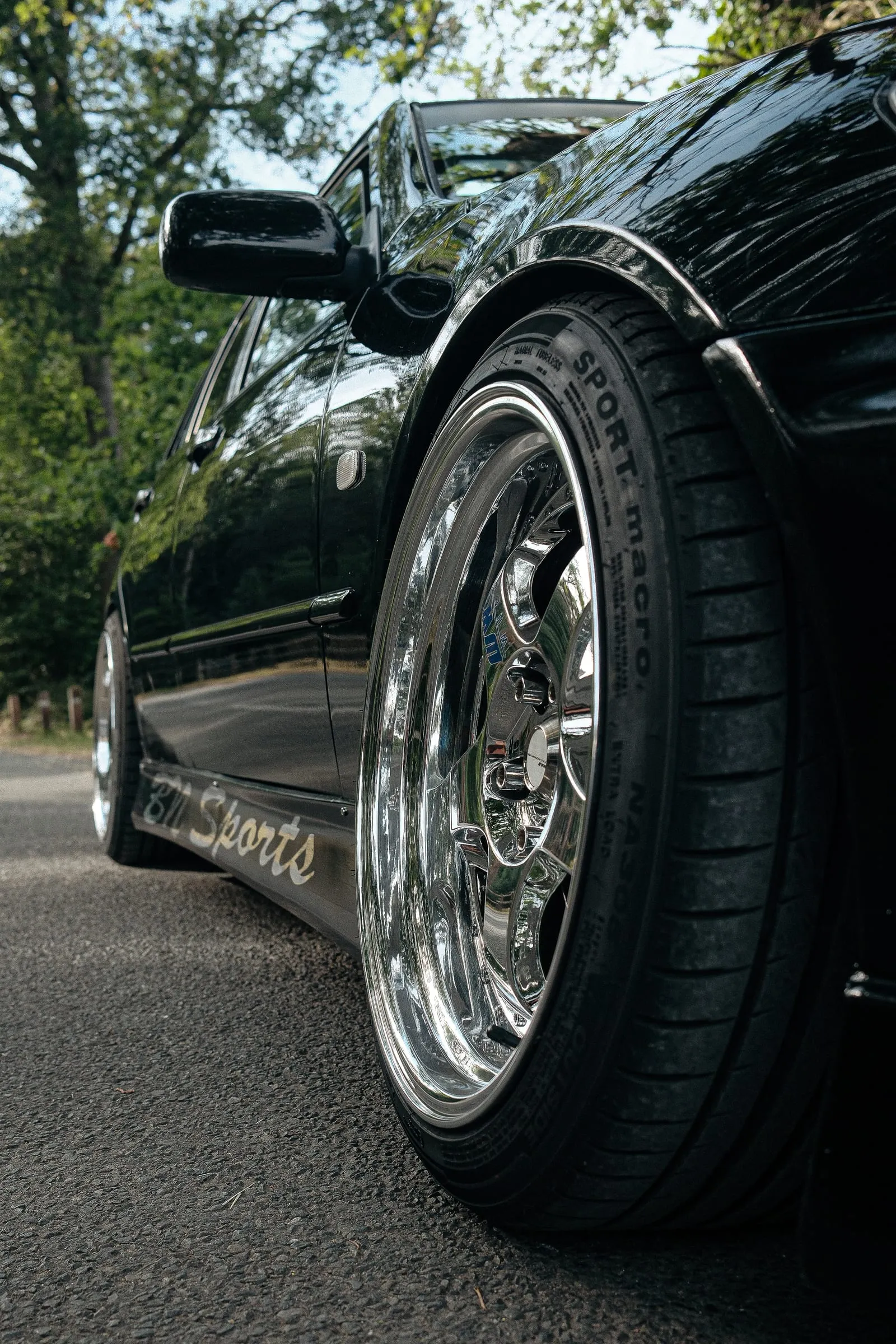 A polished chrome wheel and the car's flank, shot from the ground.