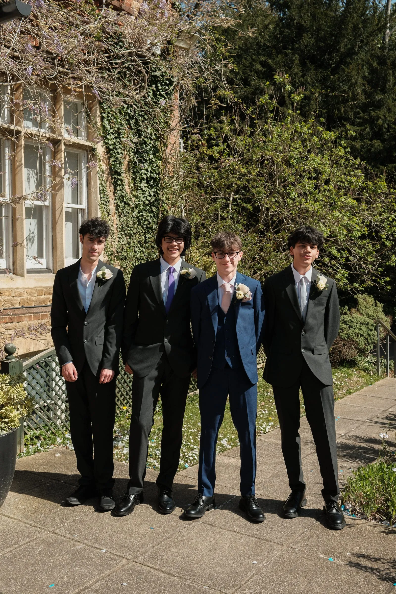 Four young men in suits stand in a row.