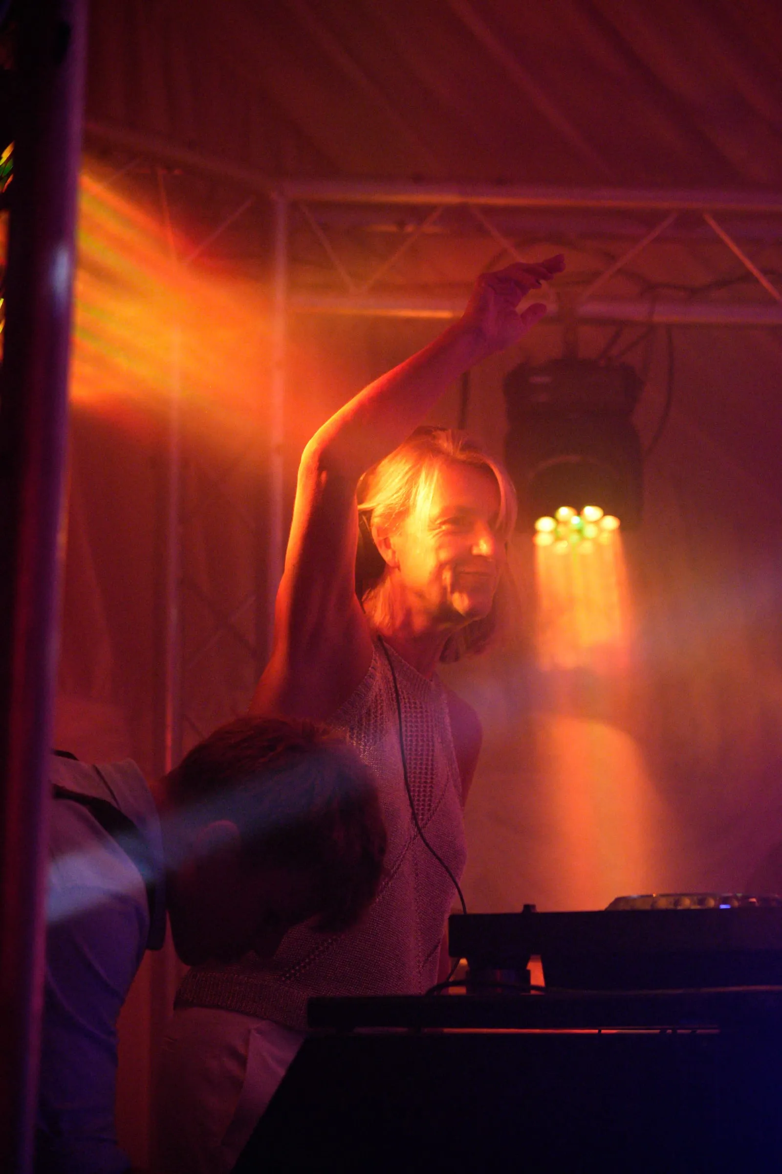 The DJ raises an arm into the haze.