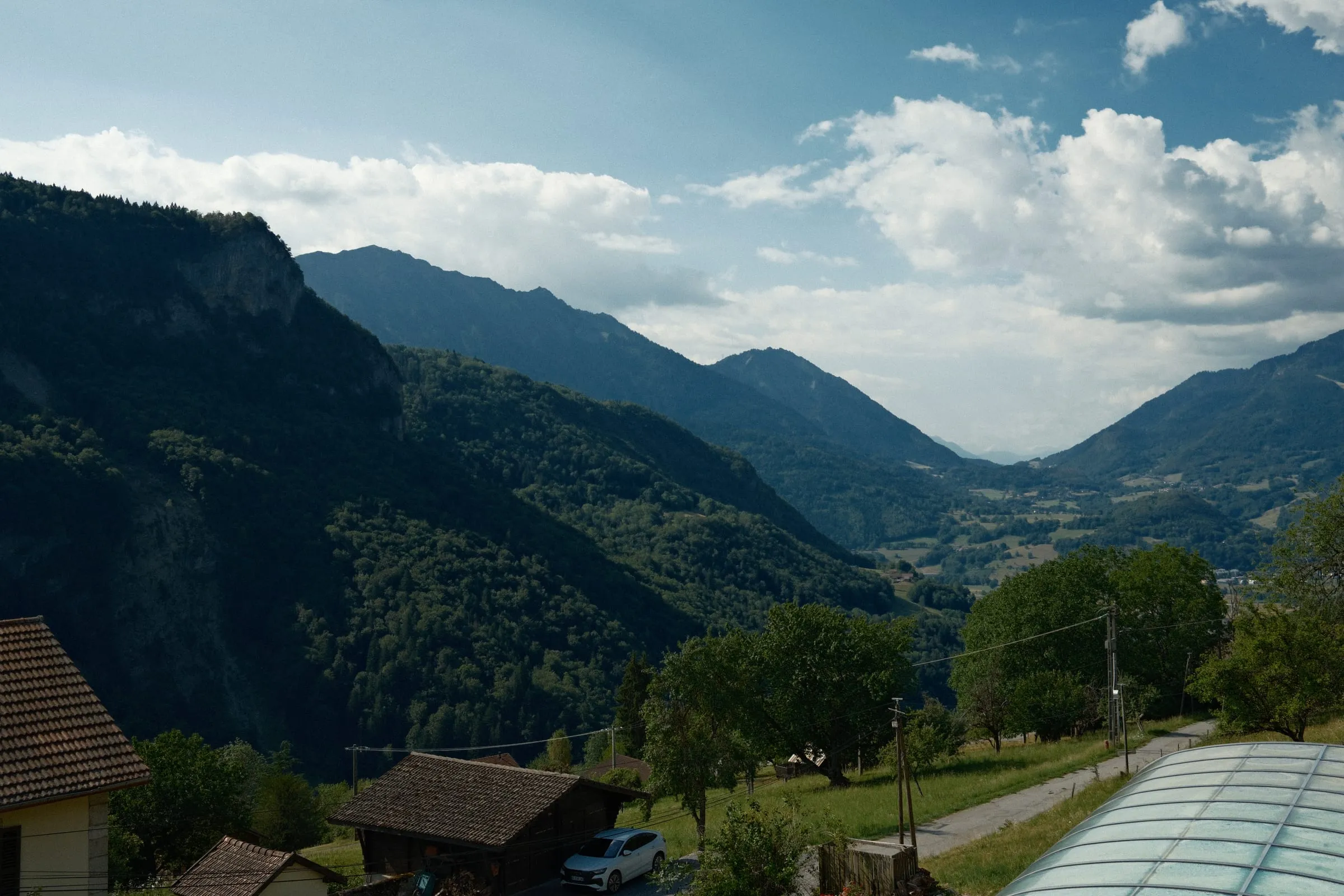 A green valley running between mountains under a summer sky.
