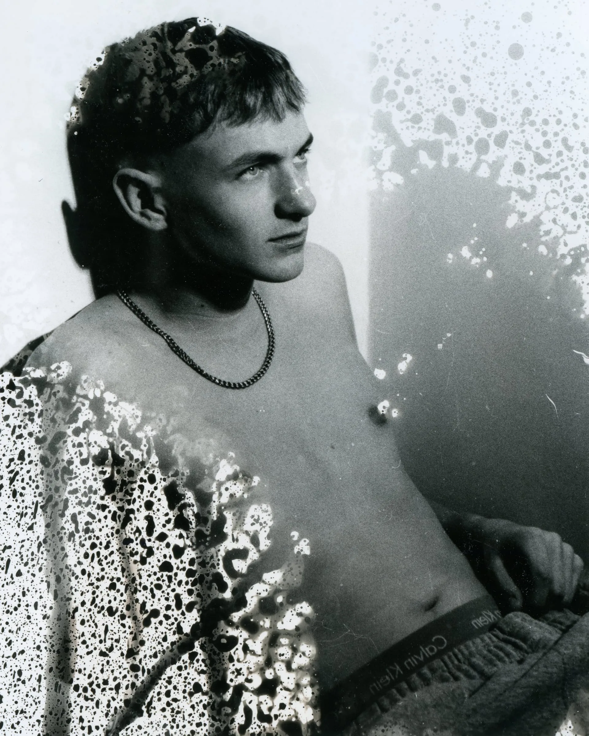A black and white portrait broken up by a mottled, bleached texture.
