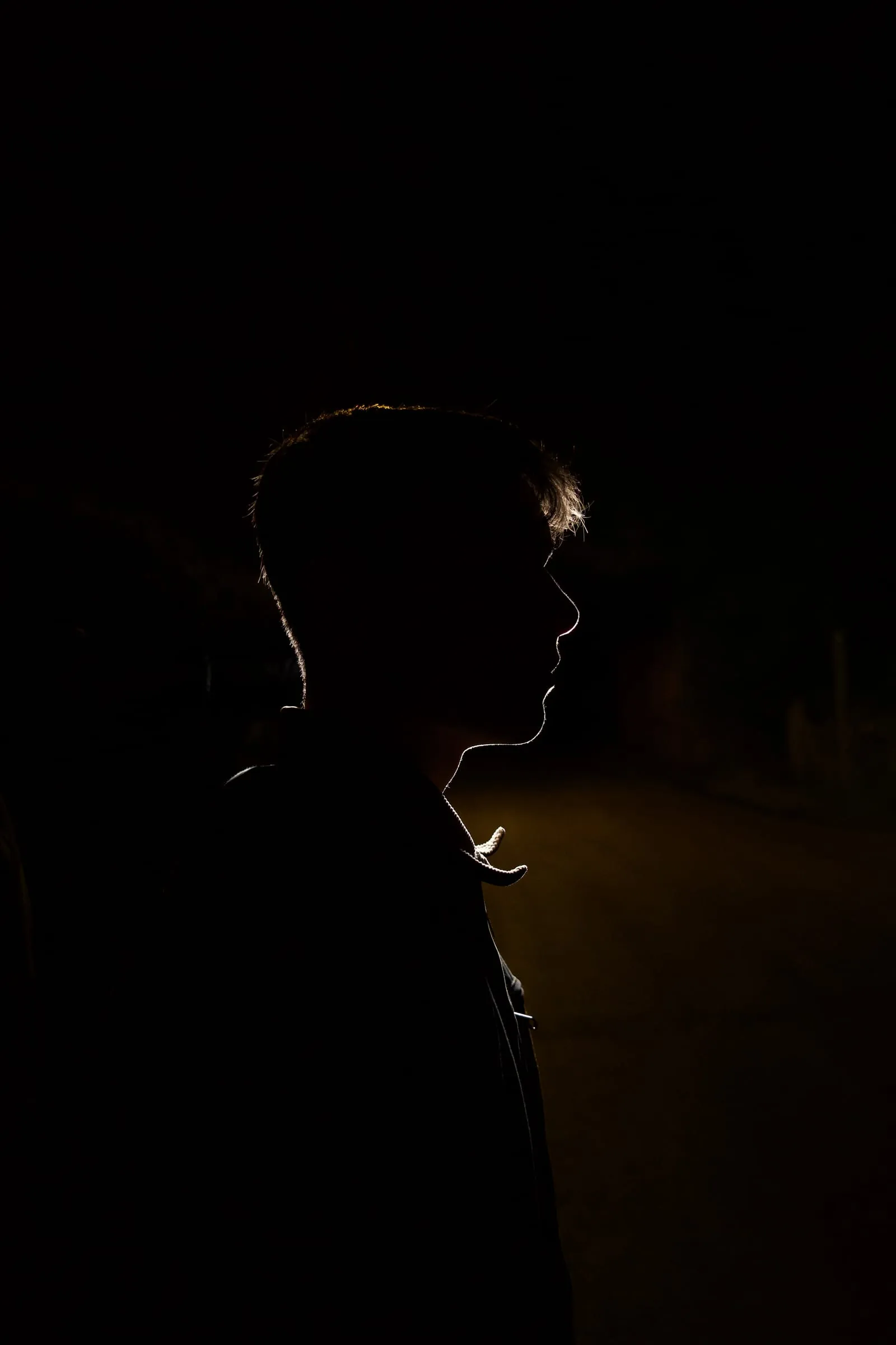 A silhouette in profile, edged with a thin line of light against the dark.